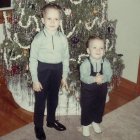 Three boys in formal attire by a decorated Christmas tree