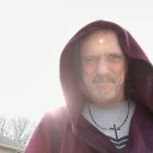 Ethereal image: Bearded man with spider on forehead in hooded cloak