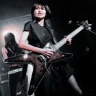 Woman Performs with Black Guitar on Stage in Spotlight