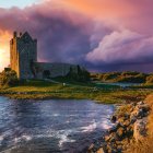 Medieval castle ruin on coastal headland at sunset with vivid clouds and rough waters