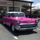 Vintage pink Chevrolet parked at retro diner with neon signs