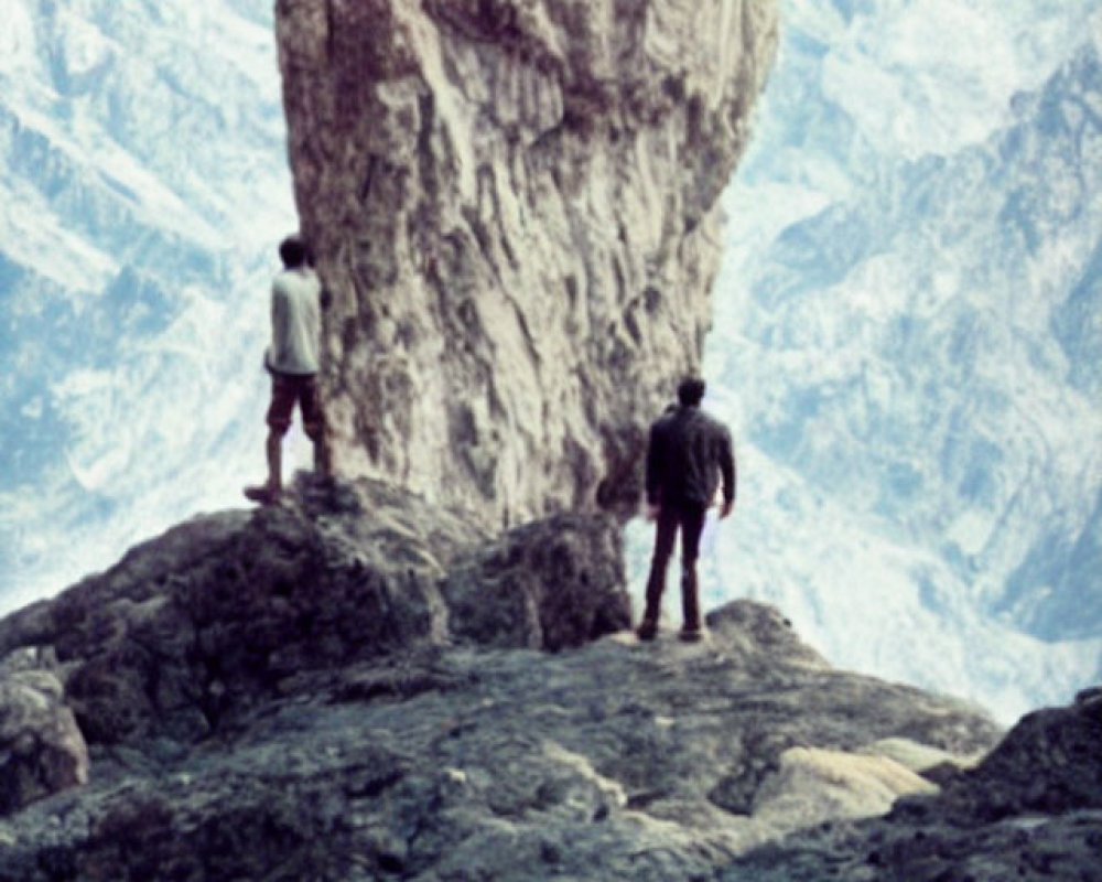 Explorers on rocky outcrop admire rugged mountain terrain