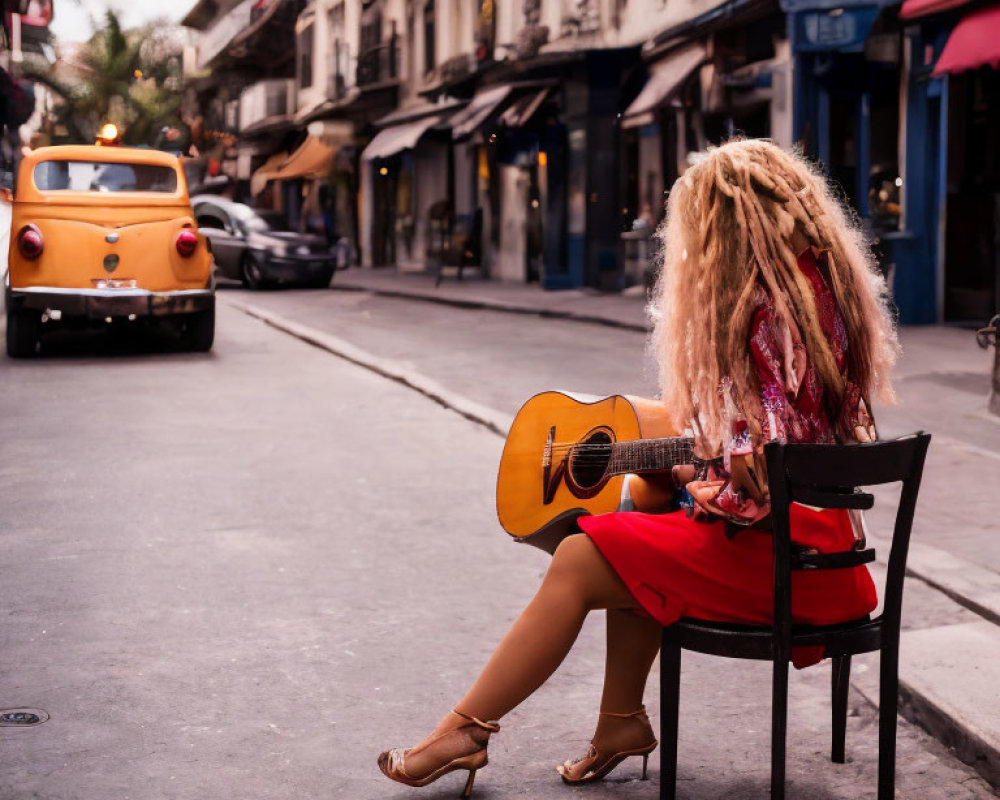 Woman with Guitar Sitting on Chair Near Vintage Car in Quaint Street