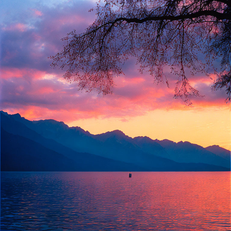 Tranquil sunset lake scene with pink and blue skies, silhouetted mountains, lone boat