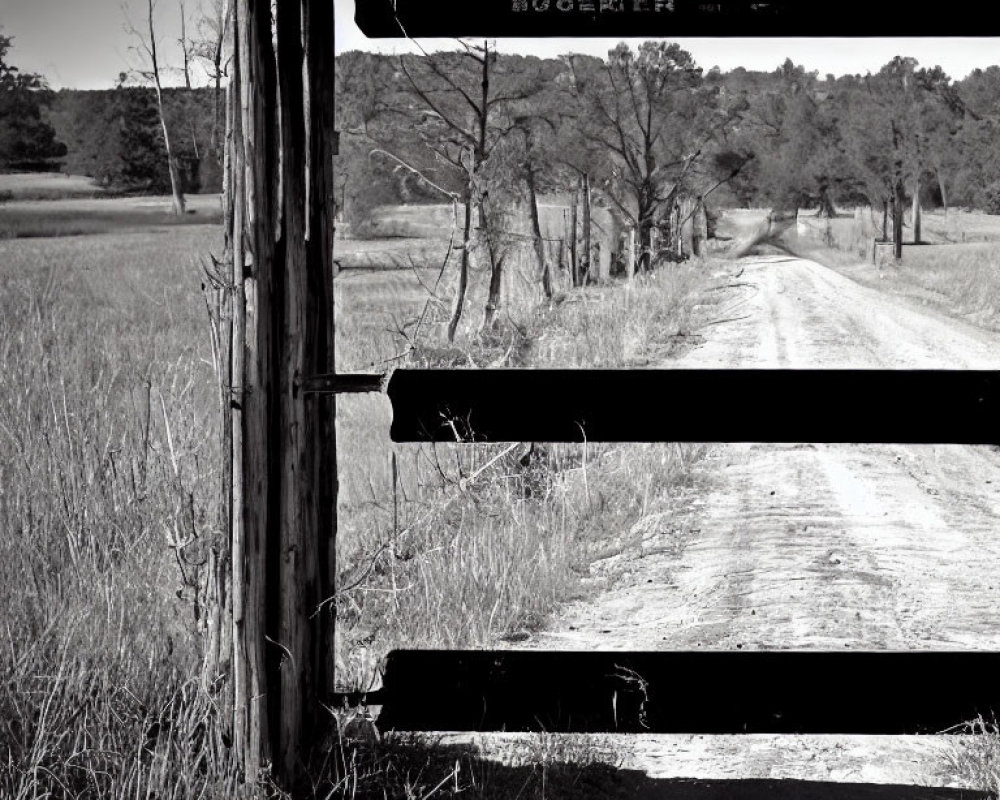 Monochrome photo of rustic wooden gate on dirt road