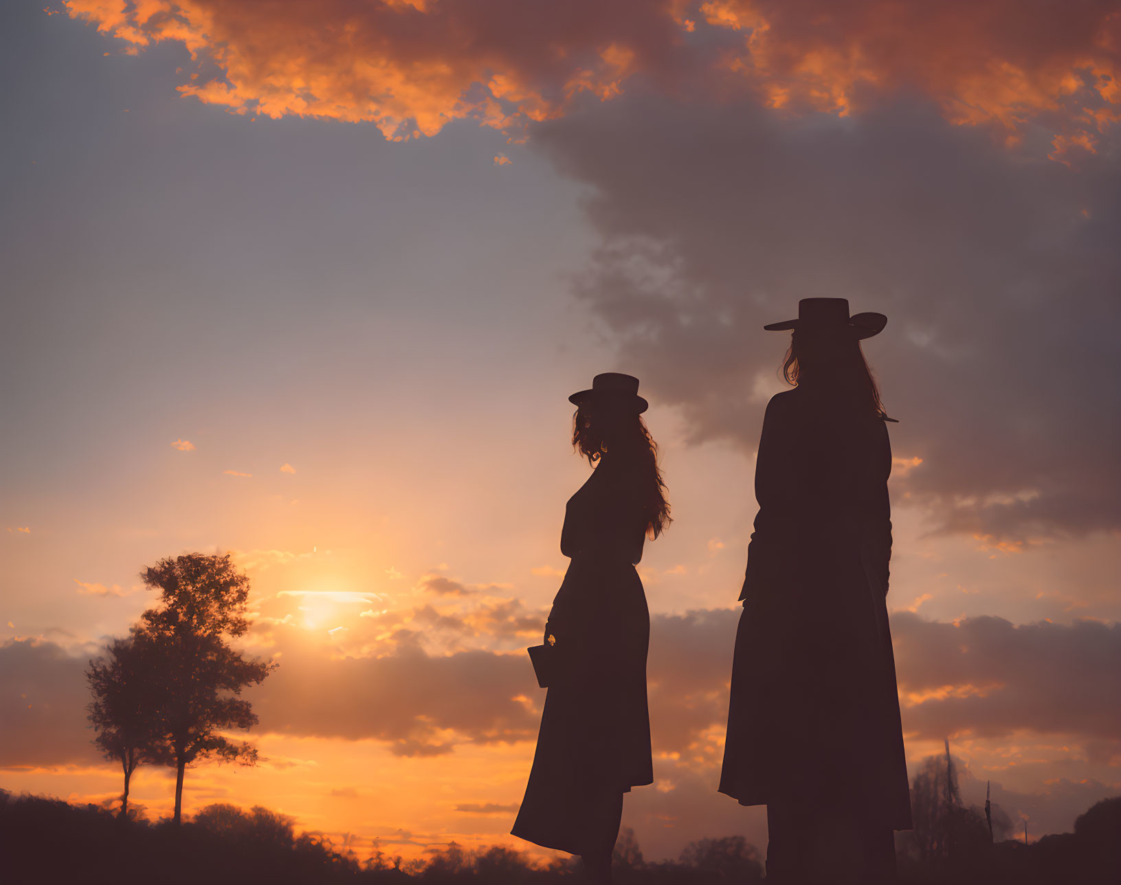 Silhouetted figures in wide-brimmed hats against vibrant sunset sky