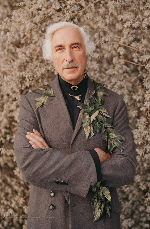 White-Haired Elderly Man in Grey Coat with Leafy Twigs on Beige Floral Background