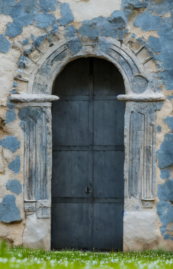 Rustic stone wall with arched wooden door and metal details