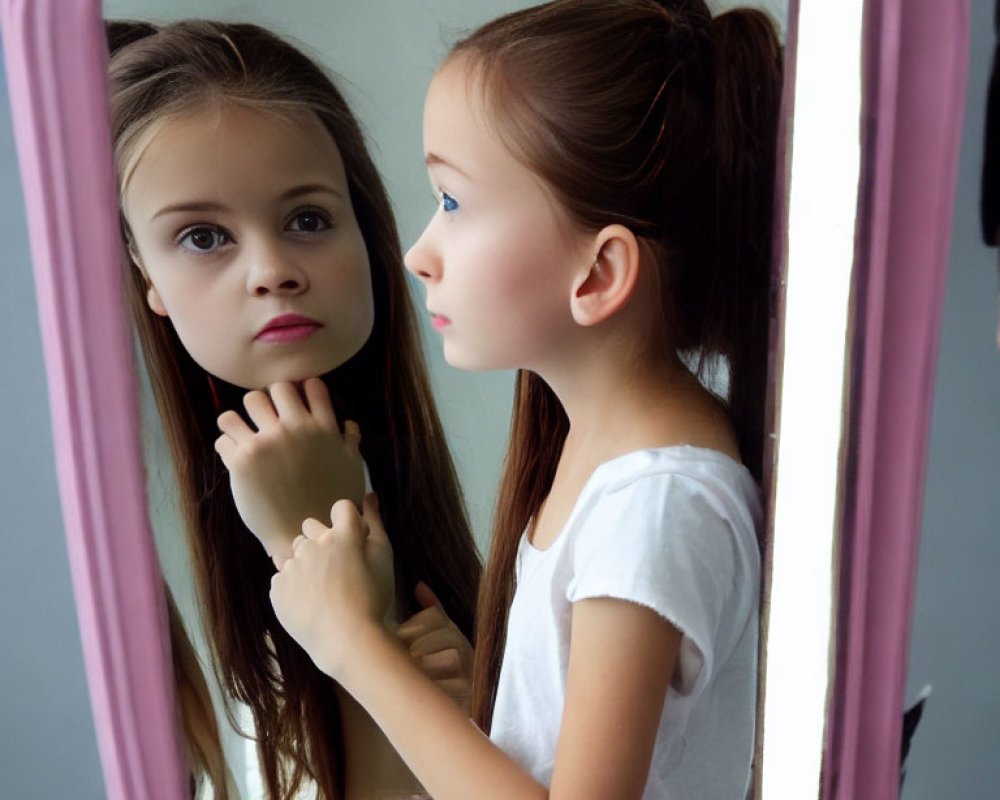 Young girl with ponytail gazes at reflection in pink-framed mirror