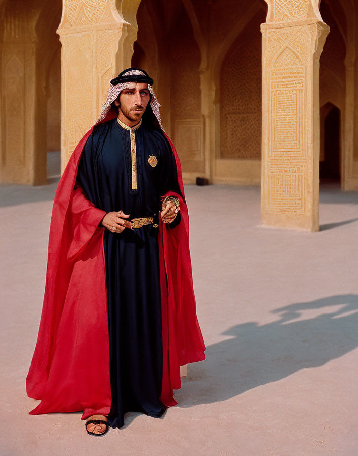 Traditional Arab man in red cloak with cane in sandstone arcade