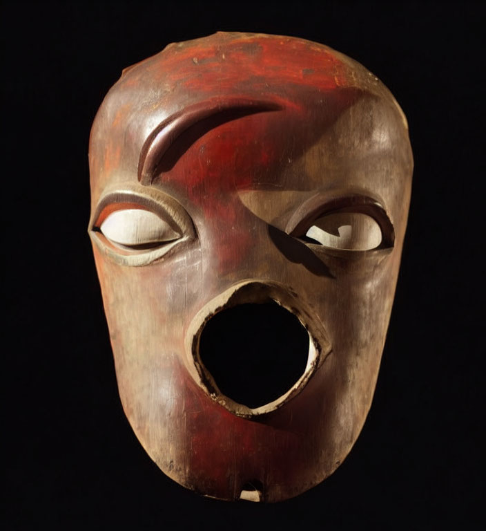 Carved wooden mask with serene expression on black background