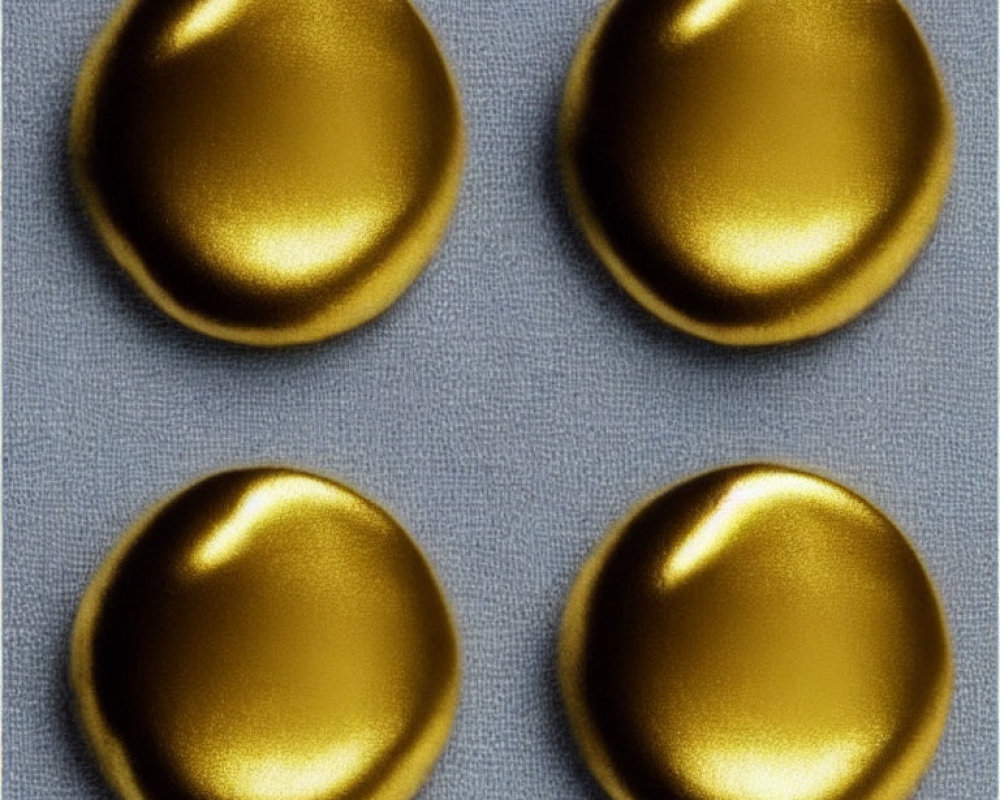 Four Gold Metallic Buttons on Textured Gray Fabric