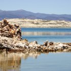 Tranquil landscape with salt formation in blue lake, desert, and mountains.