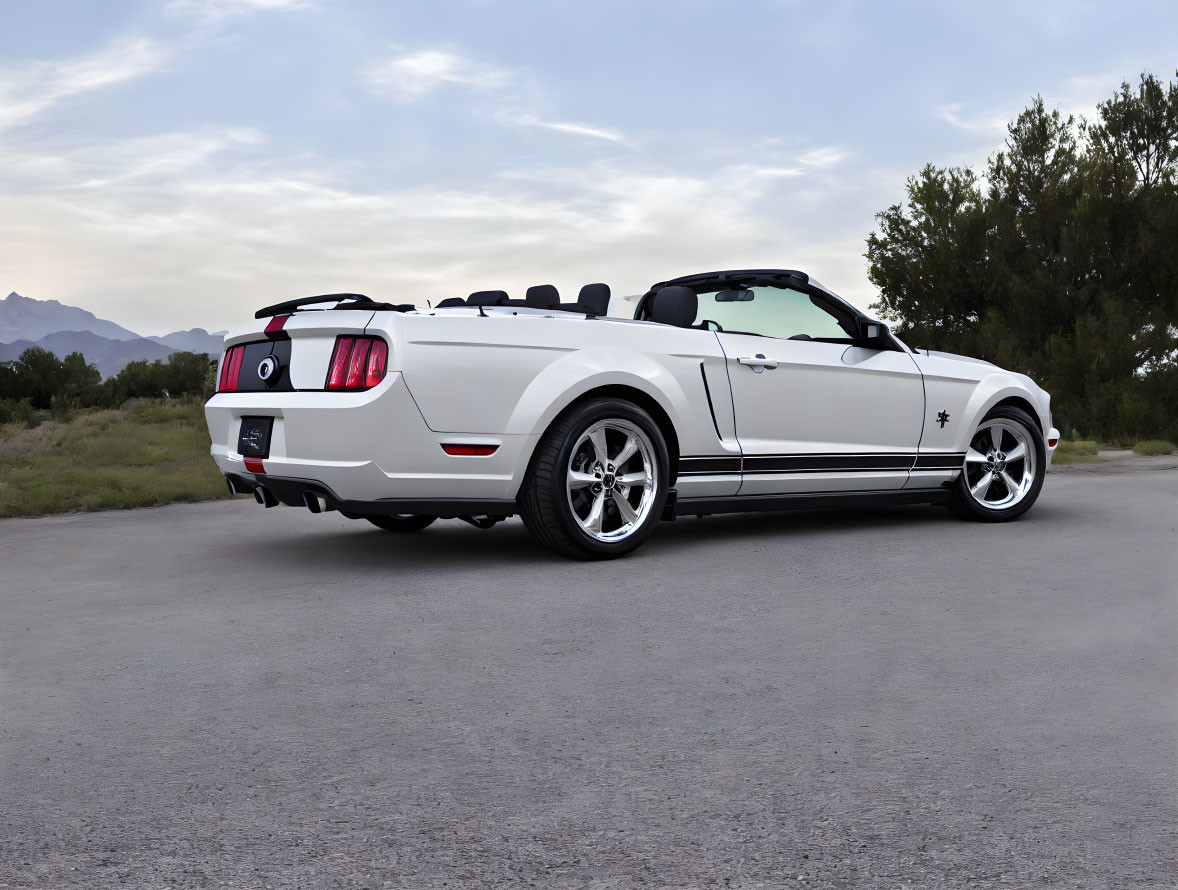 White Ford Mustang Convertible with Racing Stripes on Asphalt Road with Mountains and Trees