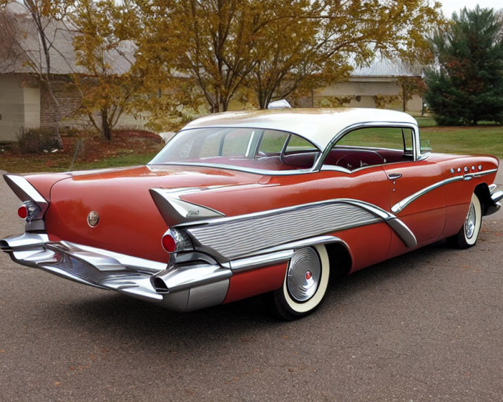 Vintage red and white car with tail fins and chrome details on asphalt road
