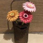 Colorful Artificial Flower Arrangement in Woven Basket on Floral Patterned Backdrop
