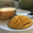 Fresh sliced mango on white plate with wooden table background
