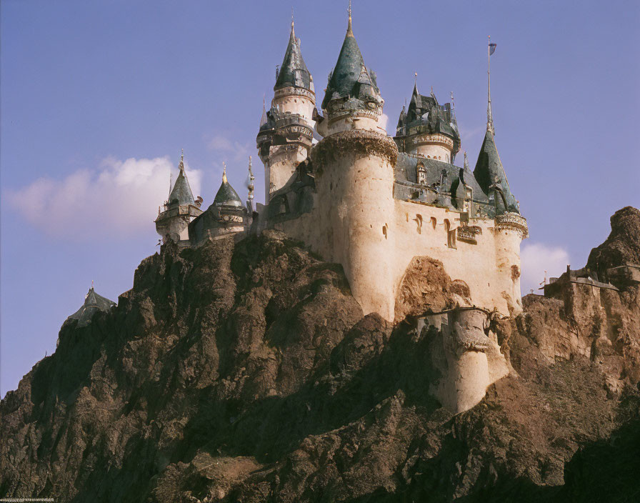 Castle with Multiple Spires on Cliff Against Blue Sky
