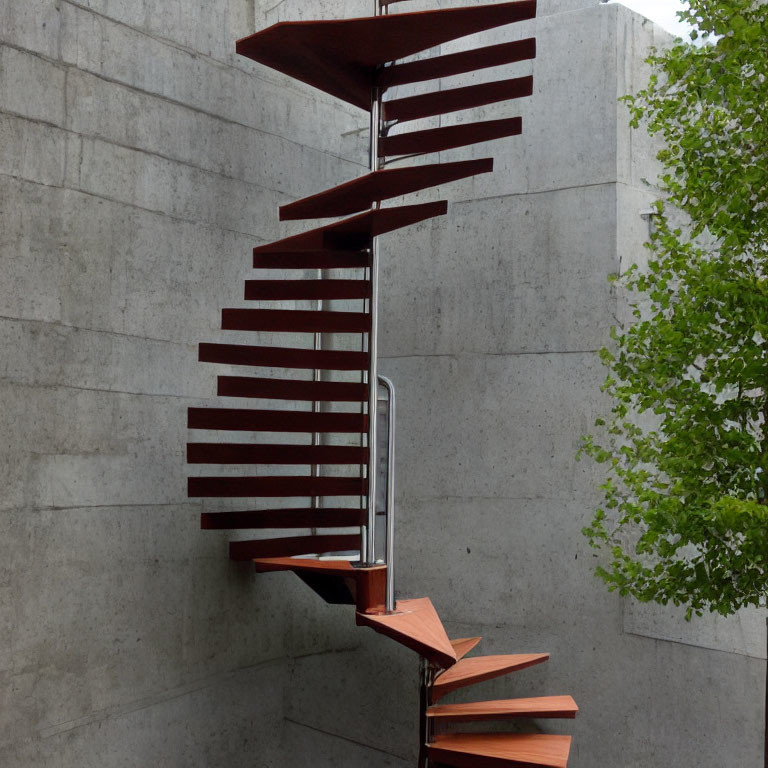 Modern spiral staircase with wooden steps and metal handrail against concrete wall and green foliage