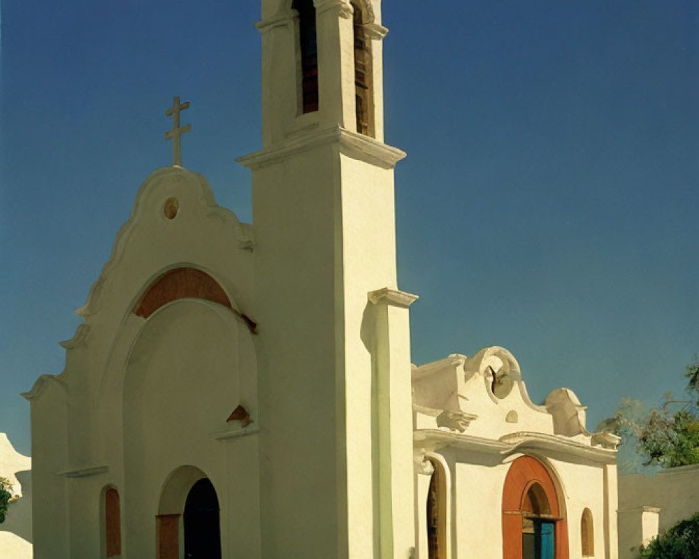 Stucco church with bell tower and cross against blue sky