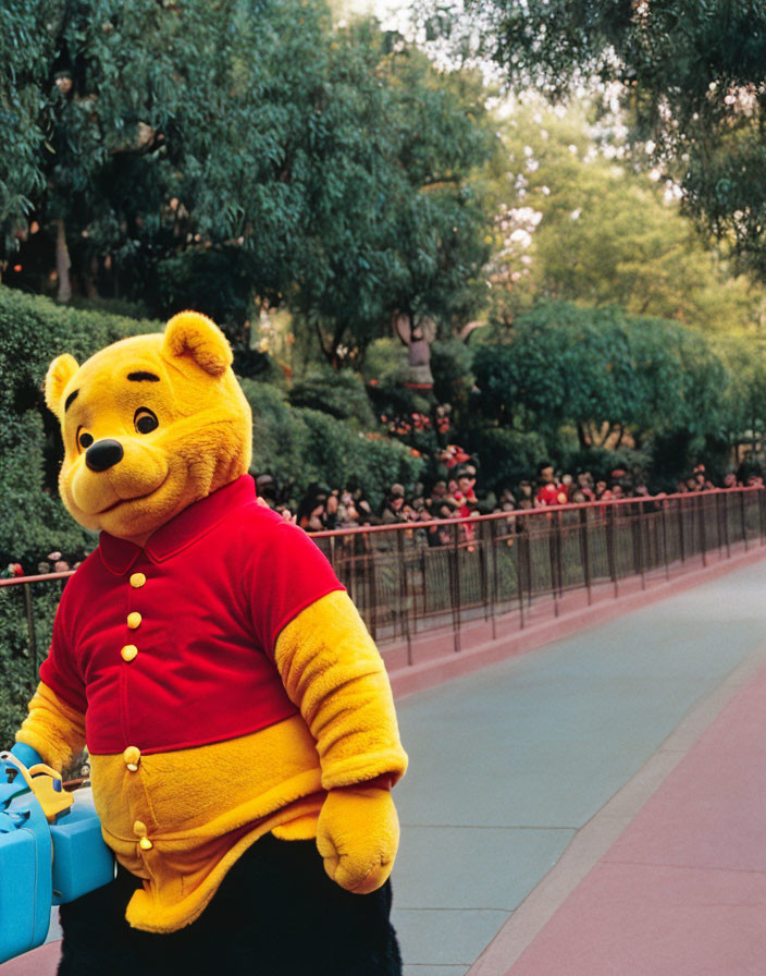 Person in Winnie the Pooh costume on pathway with blurred spectators