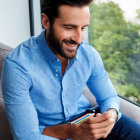 Man in Blue Shirt Smiling Indoors with Greenery View
