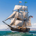 Majestic multi-masted sailing ship on ocean under cloudy sky
