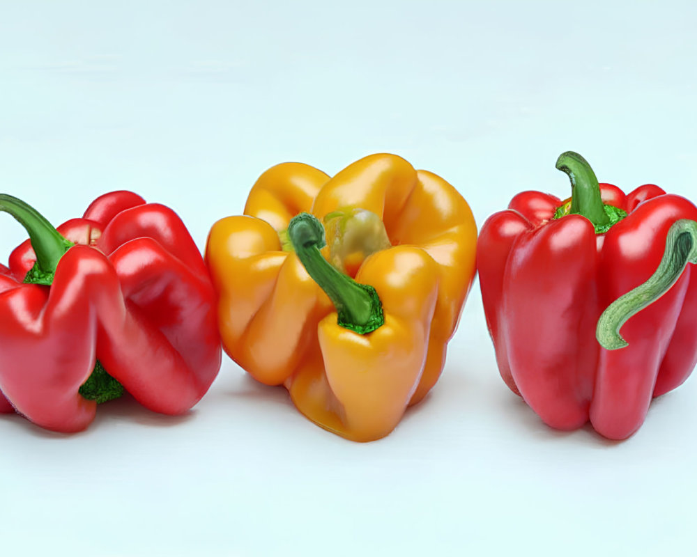 Three Bell Peppers in Red, Yellow, and Green on Light Blue Background