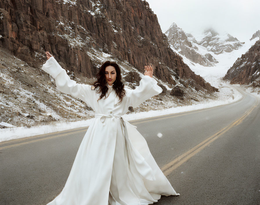 Woman in white dress on snow-covered mountain road