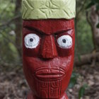 Intricately carved wooden tiki statue against forest backdrop