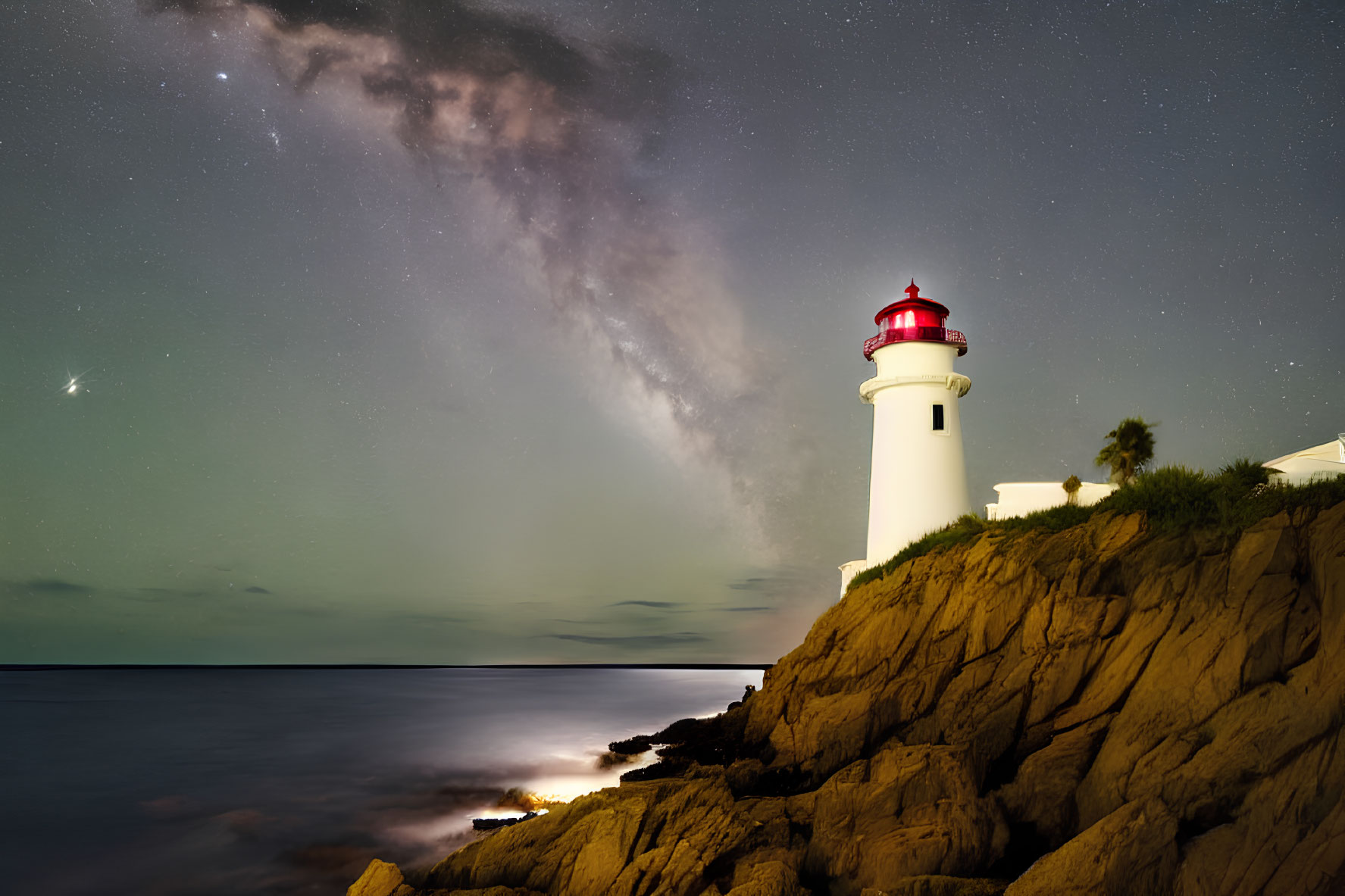 Red-topped lighthouse on cliff with starry sky and Milky Way view