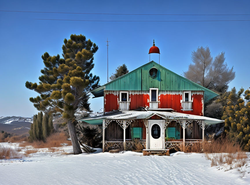 Green two-story house with red shutters and red dome roof in snowy landscape with tall pine tree and