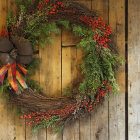 Festive Christmas wreath with pine cones, red berries, and bow on wooden door