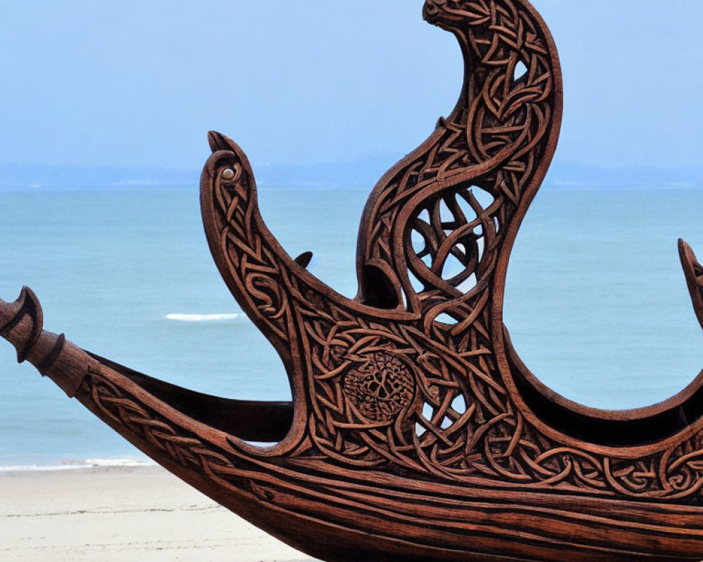 Wooden Ship Sculpture with Celtic Designs on Sandy Beach