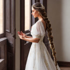 Elegant woman in white dress with beaded details and braided hairstyle by window