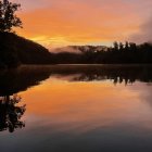 Sunrise over Tranquil Lake with Reflected Orange and Purple Hues